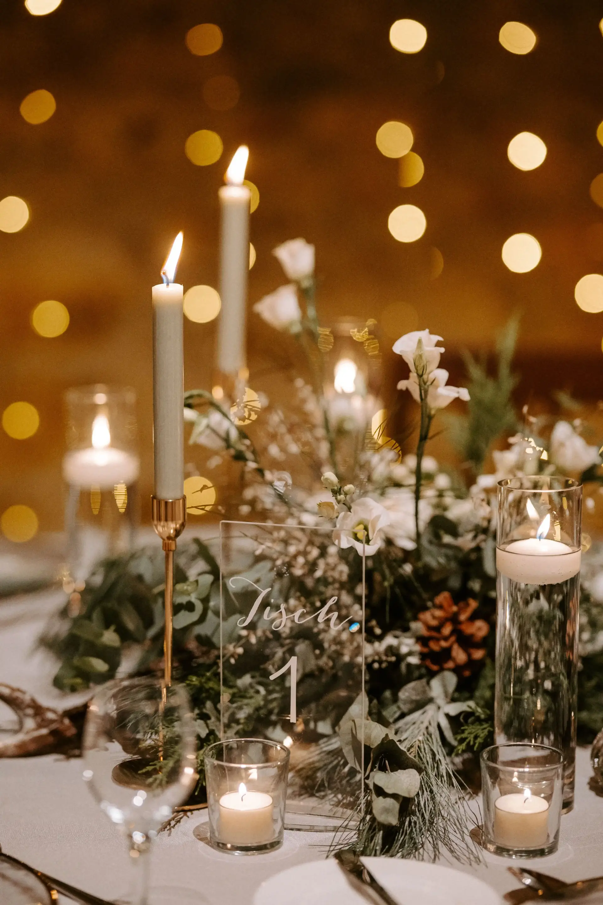 Schönes Tischarrangement im Detail mit einer Lichterkette in der Unschärfe im Hintergrund.